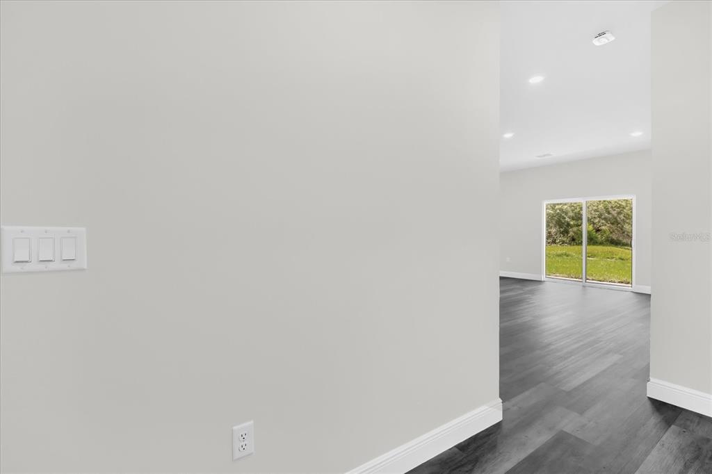 A view of a light-walled hallway leading to a room with dark flooring and sliding doors — 17190 SW 44TH CIRCLE, OCALA, FL