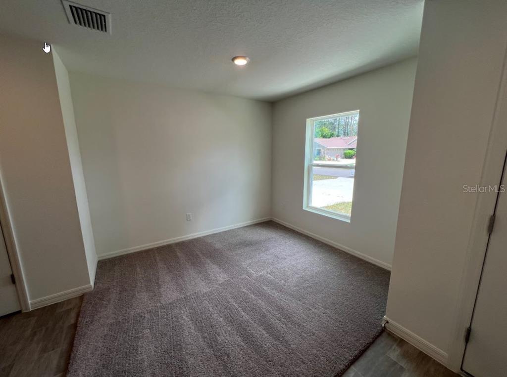 An empty bedroom features neutral walls, gray carpeting, a single window, and a recessed ceiling light — 25 RYDING LANE, PALM COAST, FL