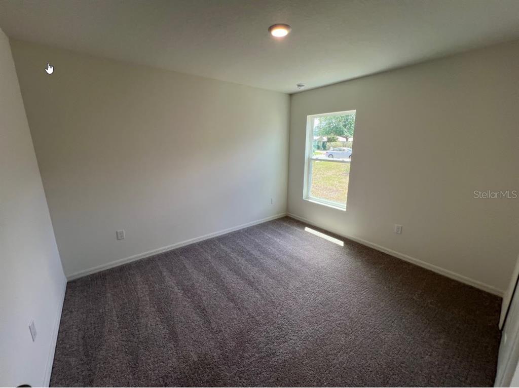 An empty bedroom features neutral walls, gray carpet, and a single window — 25 RYDING LANE, PALM COAST, FL