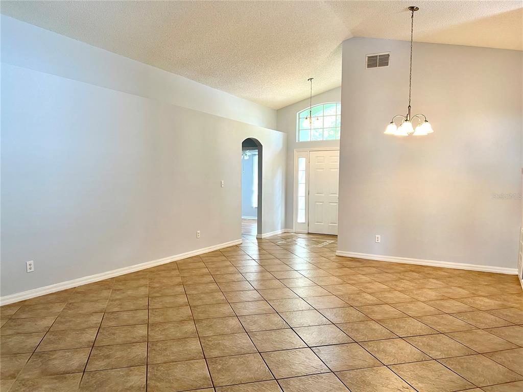 A spacious room with light blue walls, diagonal tile flooring, and a vaulted ceiling — 80 PINE FOREST PLACE, APOPKA, FL