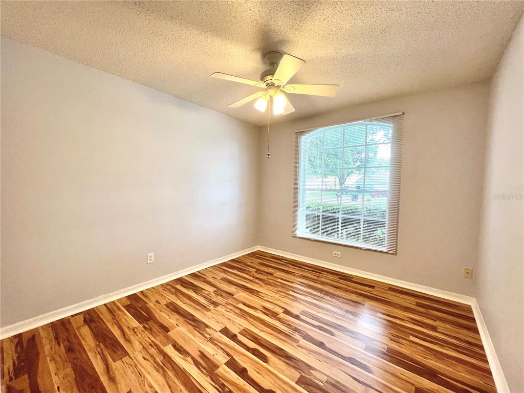 An empty bedroom features light gray walls, a ceiling fan, and wood-look laminate flooring — 80 PINE FOREST PLACE, APOPKA, FL
