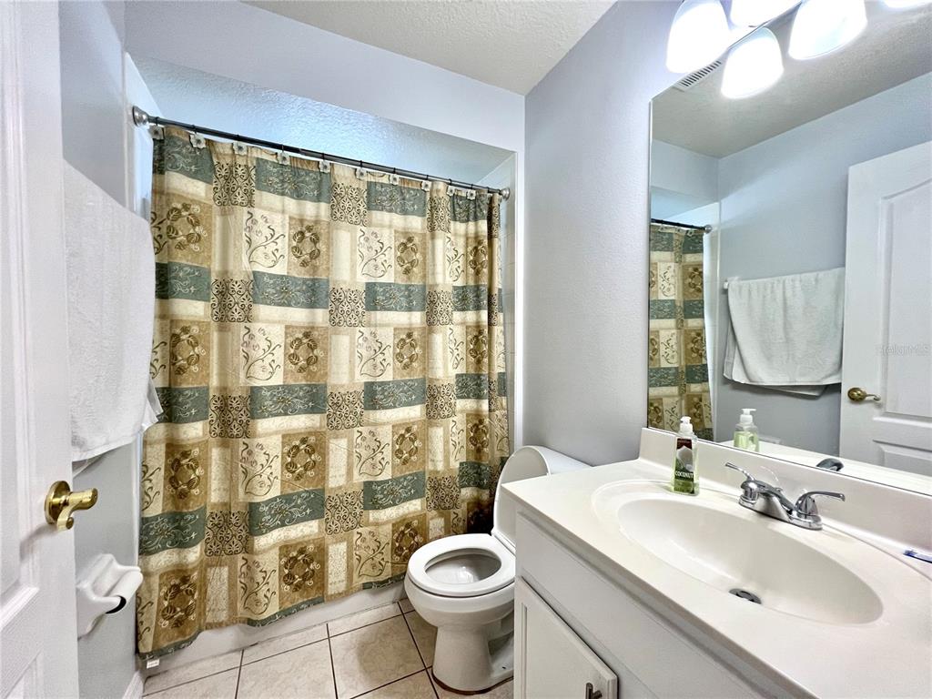 A bathroom features a patterned shower curtain, a white toilet, and a vanity with sink — 80 PINE FOREST PLACE, APOPKA, FL
