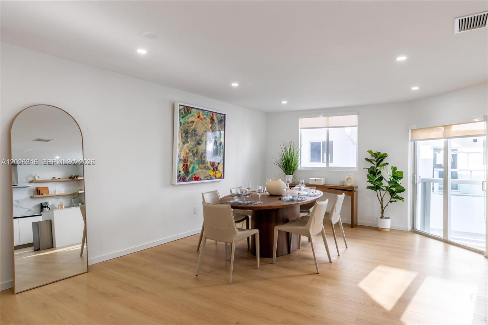 A dining room features a wooden table, light-colored chairs, a large mirror, and artwork — 1975 Calais Dr # 4, Miami Beach FL 33141, MIAMI BEACH, FL
