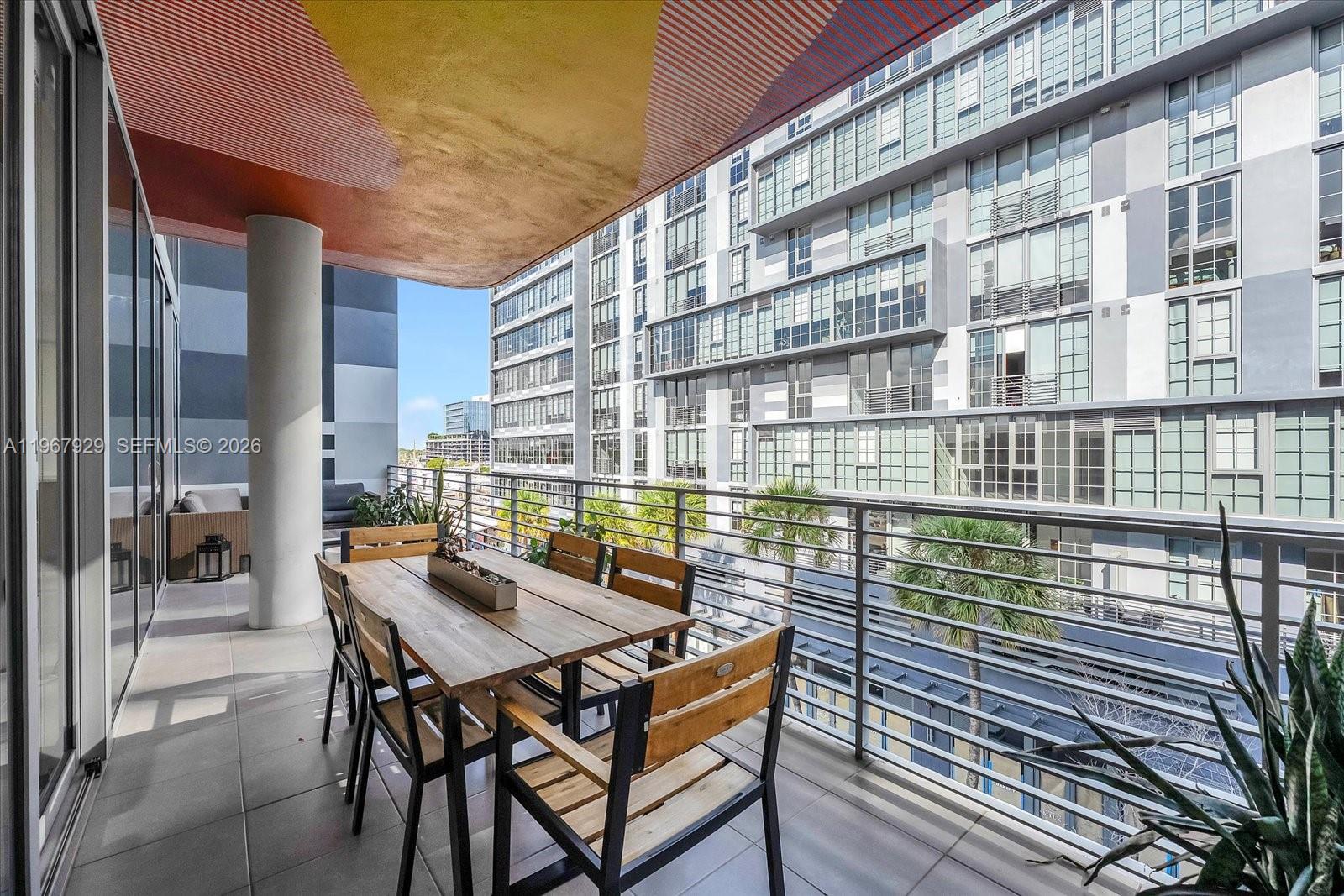 A balcony features a wooden dining set, a decorative ceiling, and a metal railing — 250 NW 24th St # 4A, Miami FL 33127, MIAMI, FL