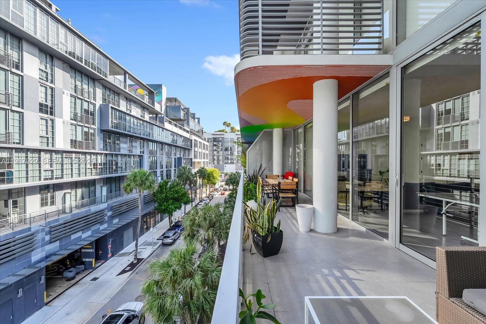 A balcony with a colorful ceiling overlooks a city street lined with palm trees — 250 NW 24th St # 4A, Miami FL 33127, MIAMI, FL