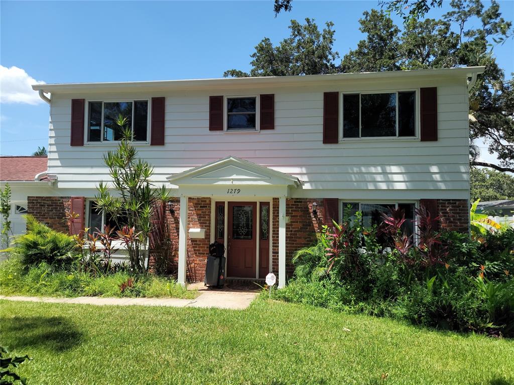 A two-story house with white siding, brick accents, and a covered front entryway — 1279 86TH AVENUE N, ST PETERSBURG, FL