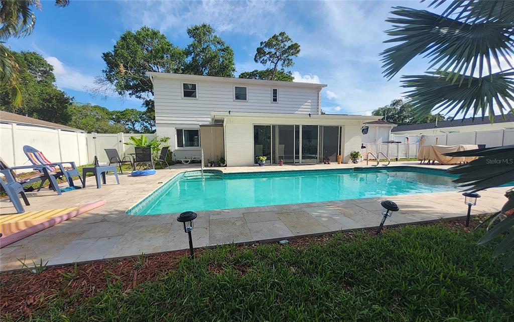 A two-story white house features a backyard swimming pool with a stone patio — 1279 86TH AVENUE N, ST PETERSBURG, FL
