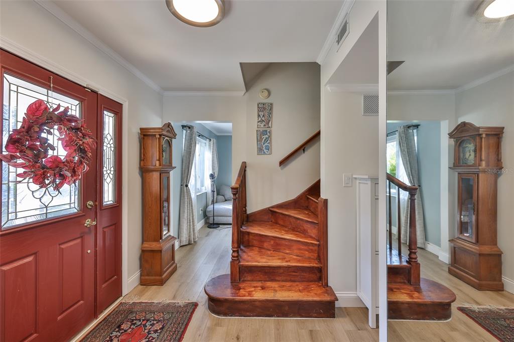 An entryway features a red front door, a wooden staircase, and a grandfather clock — 1279 86TH AVENUE N, ST PETERSBURG, FL