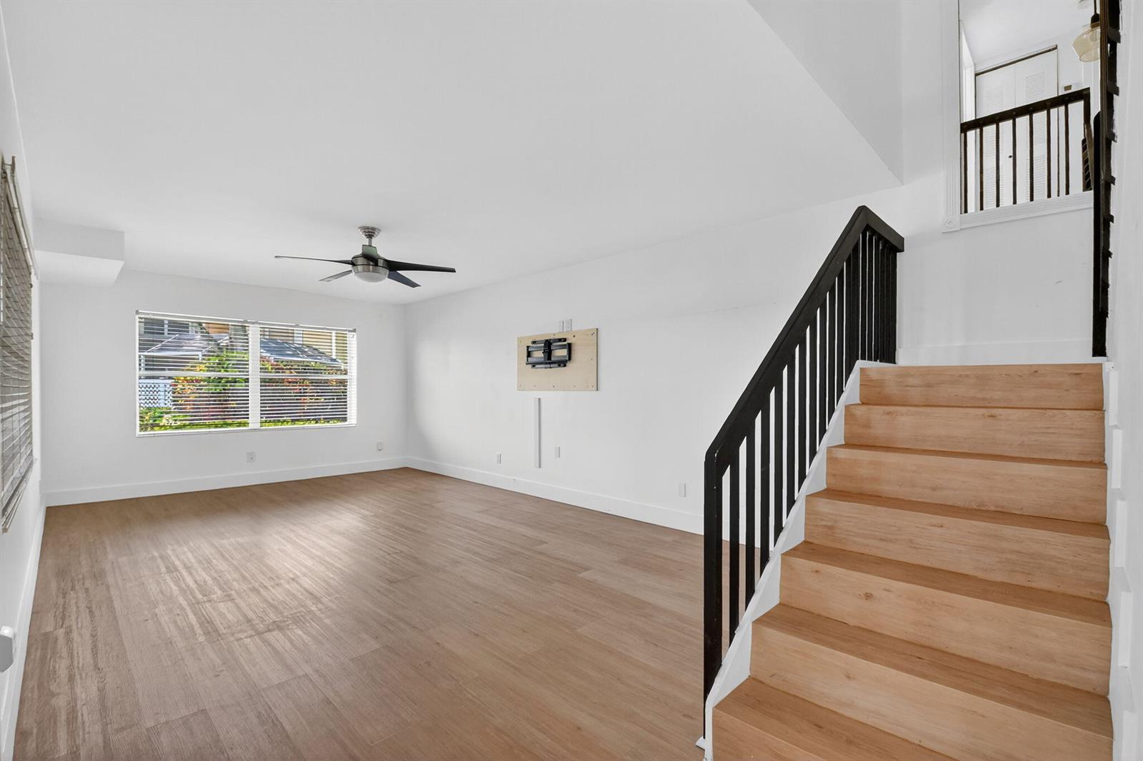 An empty living room features light wood flooring, white walls, a ceiling fan, and stairs — 3404 Hayden Court, Boynton Beach FL 33436, BOYNTON BEACH, FL