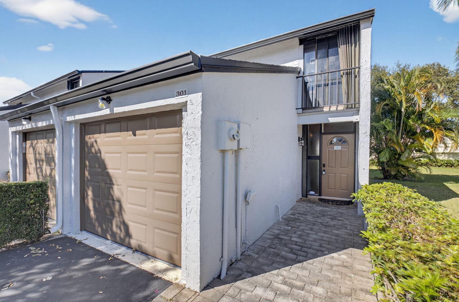 A two-story townhouse exterior features a brown garage door, a front entrance, and a balcony — 4761 NW 2nd Avenue # 301, Boca Raton FL 33431, BOCA RATON, FL