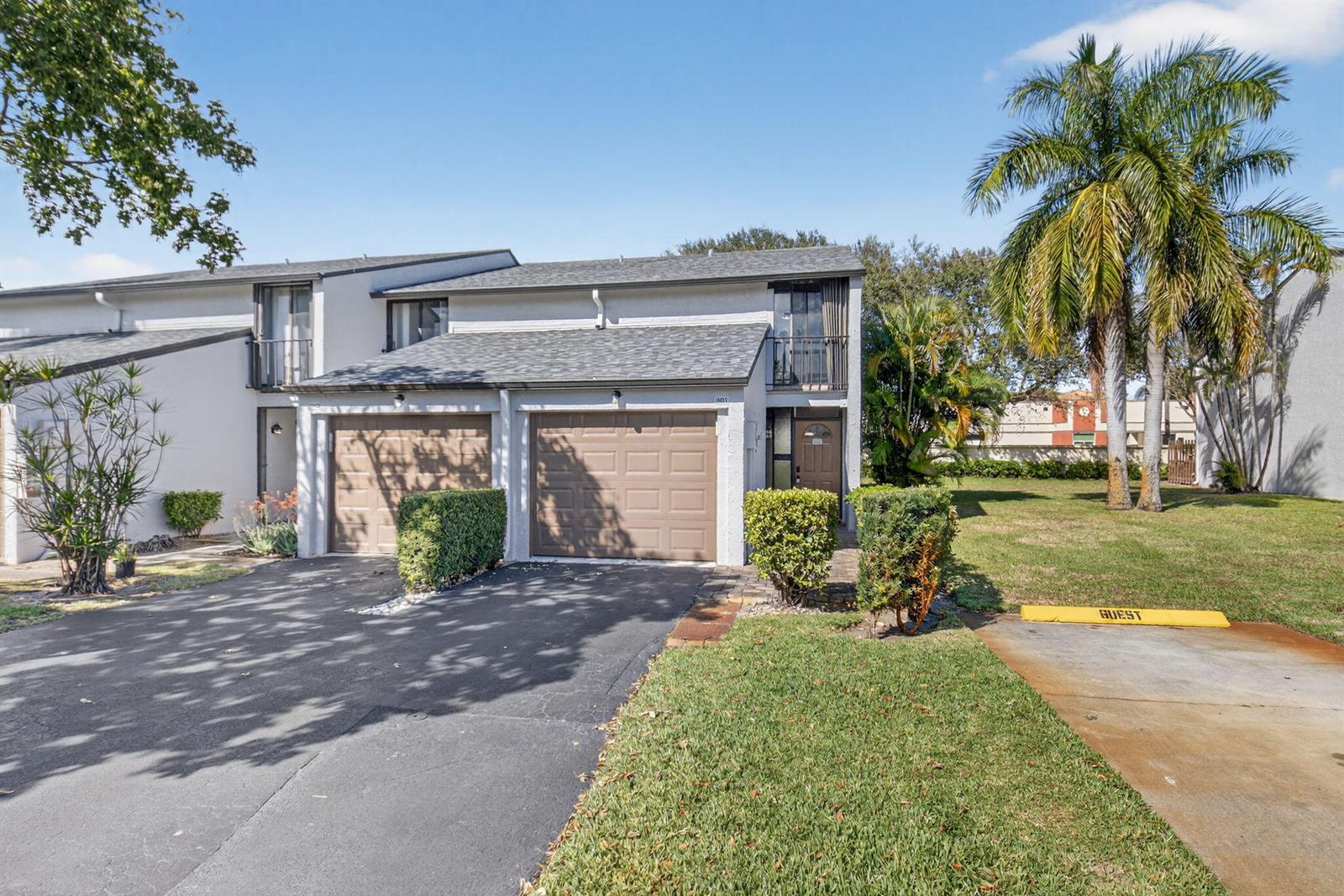 A two-story townhouse exterior features a gray roof, tan garage doors, and a palm tree — 4761 NW 2nd Avenue # 301, Boca Raton FL 33431, BOCA RATON, FL
