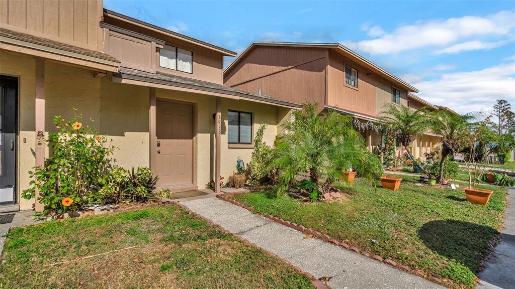 A tan townhouse exterior features a front walkway, a brown door, and small potted palms — 3913 OAK LIMB COURT, TAMPA, FL