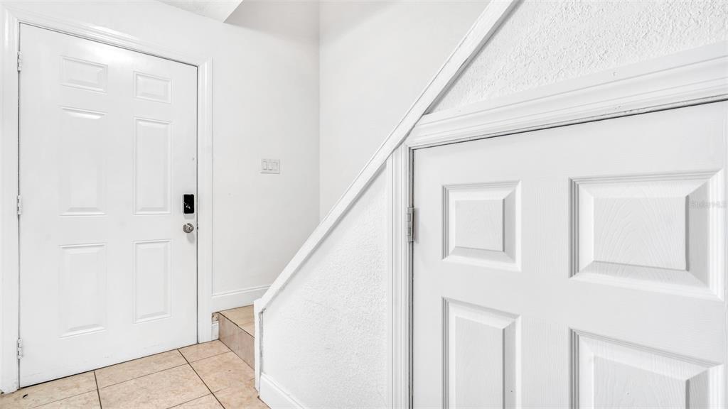 An interior view shows a white front door and a storage door under a staircase — 3913 OAK LIMB COURT, TAMPA, FL