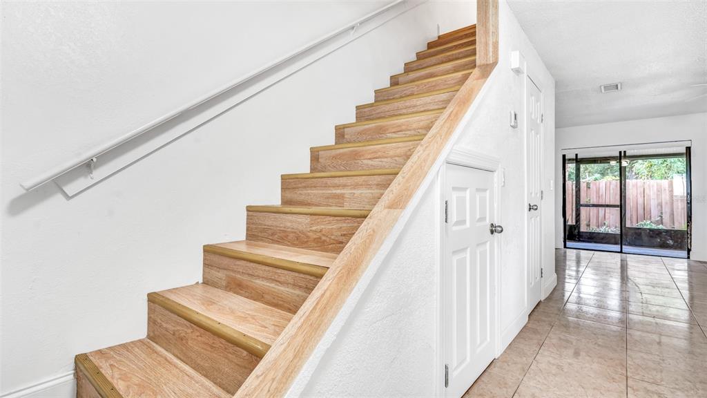A staircase with wood-look treads and a white handrail sits beside a white door — 3913 OAK LIMB COURT, TAMPA, FL