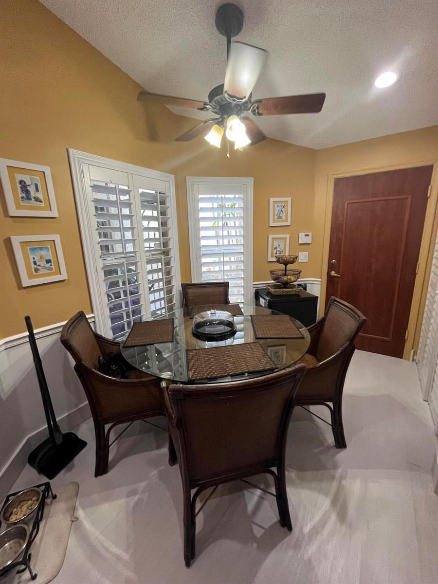 A dining area features a glass-topped table, four wicker chairs, and a ceiling fan — 6108 Petunia Road, Delray Beach FL 33484, DELRAY BEACH, FL