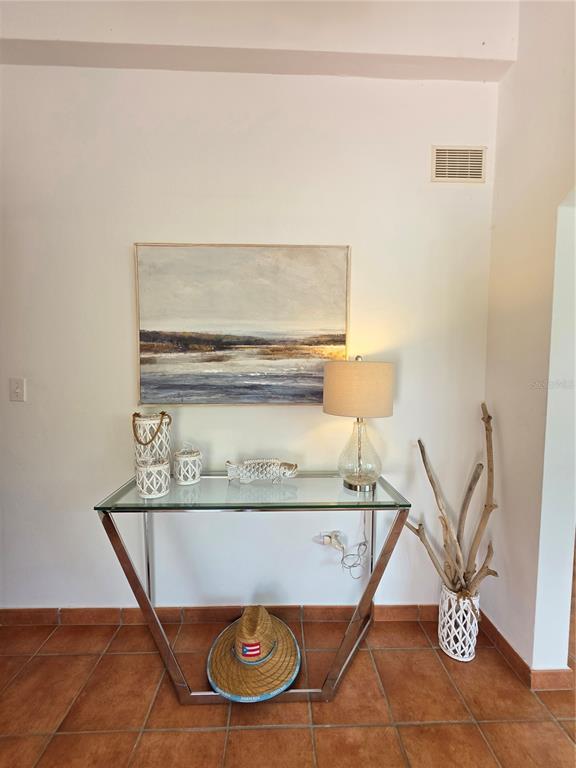 A glass-topped console table sits against a white wall beneath a landscape painting — 6000 RIO MAR BOULEVARD, RIO GRANDE, PR