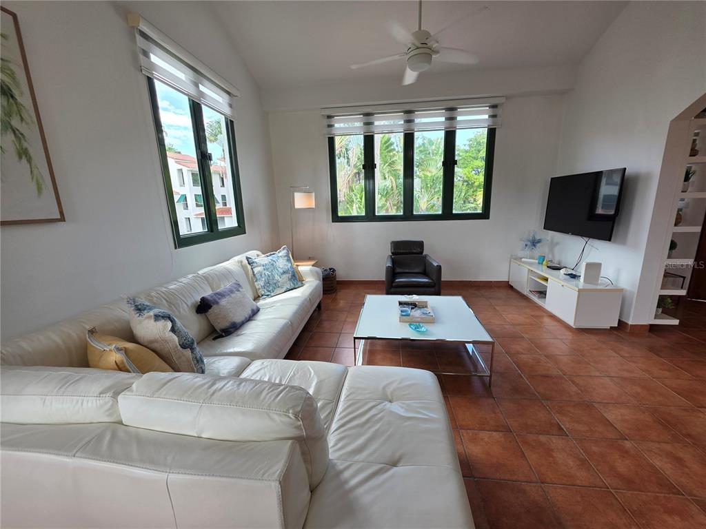 A living room features a white sectional sofa, a coffee table, and a wall-mounted television — 6000 RIO MAR BOULEVARD, RIO GRANDE, PR