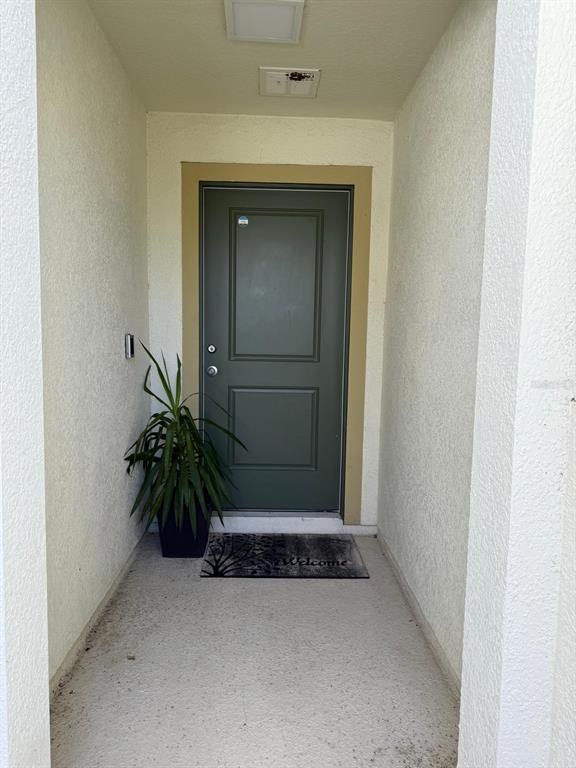 A covered entryway features a dark green front door, a potted plant, and a welcome mat — 3230 BAYOU LANE, TAVARES, FL