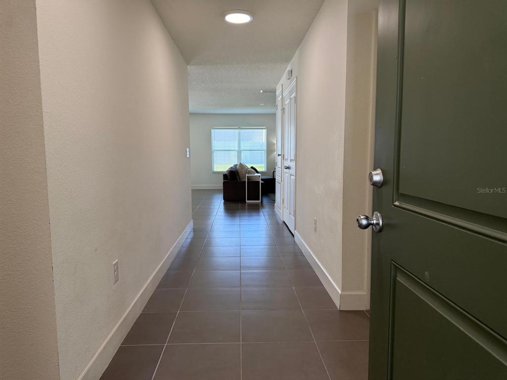 A tiled hallway leads from an open doorway toward a living area with a window — 3230 BAYOU LANE, TAVARES, FL