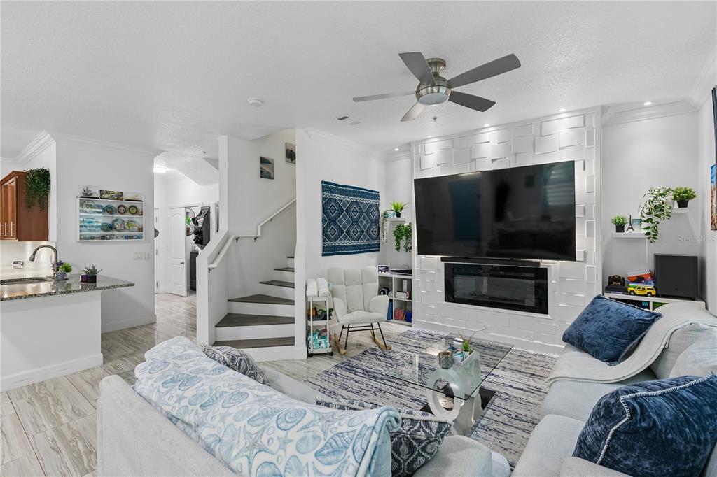 A living room features a large television mounted above a fireplace on a textured wall — 2264 BETSY ROSS LANE UNIT 2264, ST CLOUD, FL