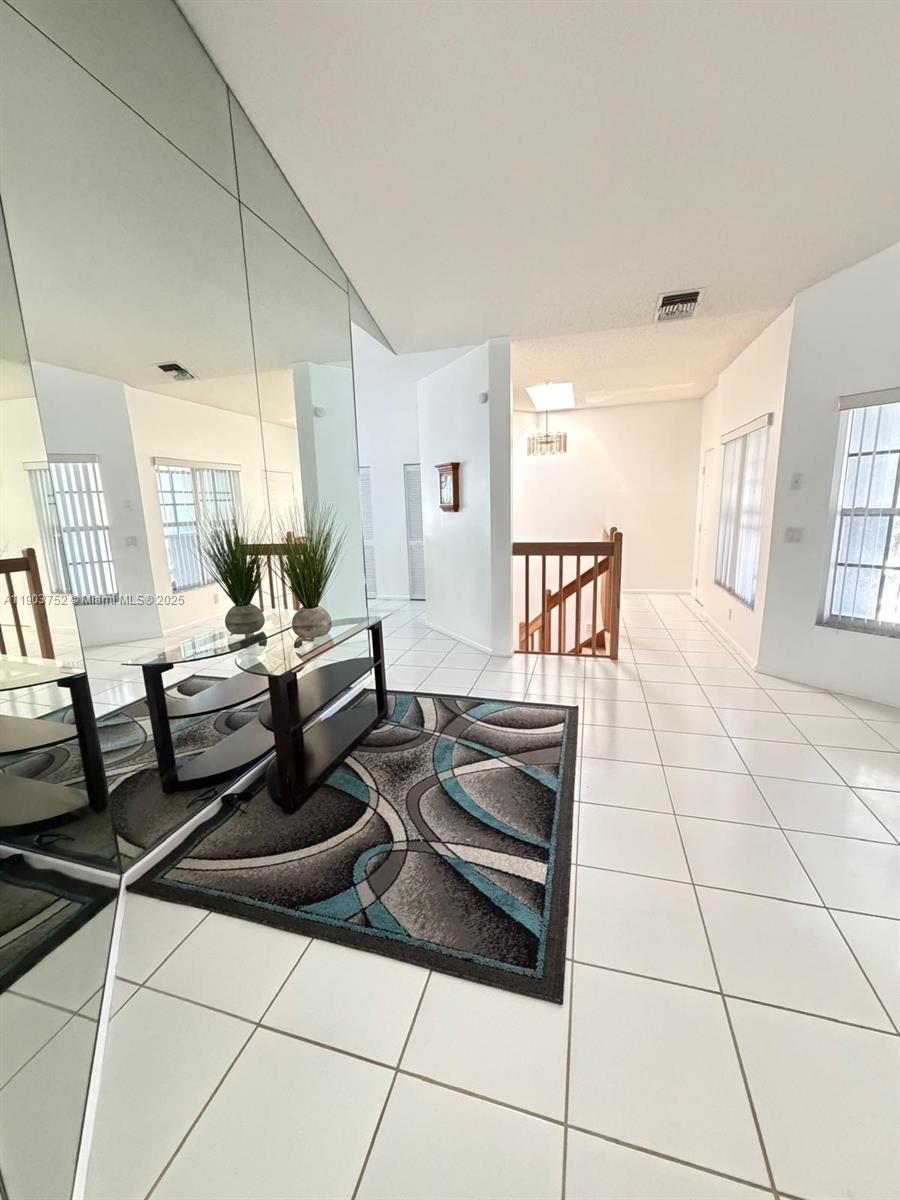 A tiled entryway features a large mirror, a glass console table, and a patterned rug — 11690 Briarwood Cir # 4, Boynton Beach FL 33437, BOYNTON BEACH, FL