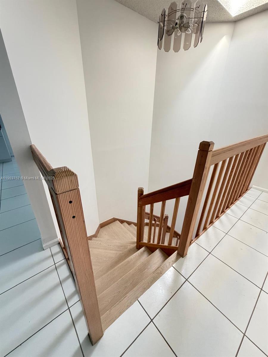 A wooden staircase with a railing leads down from a white-tiled landing — 11690 Briarwood Cir # 4, Boynton Beach FL 33437, BOYNTON BEACH, FL