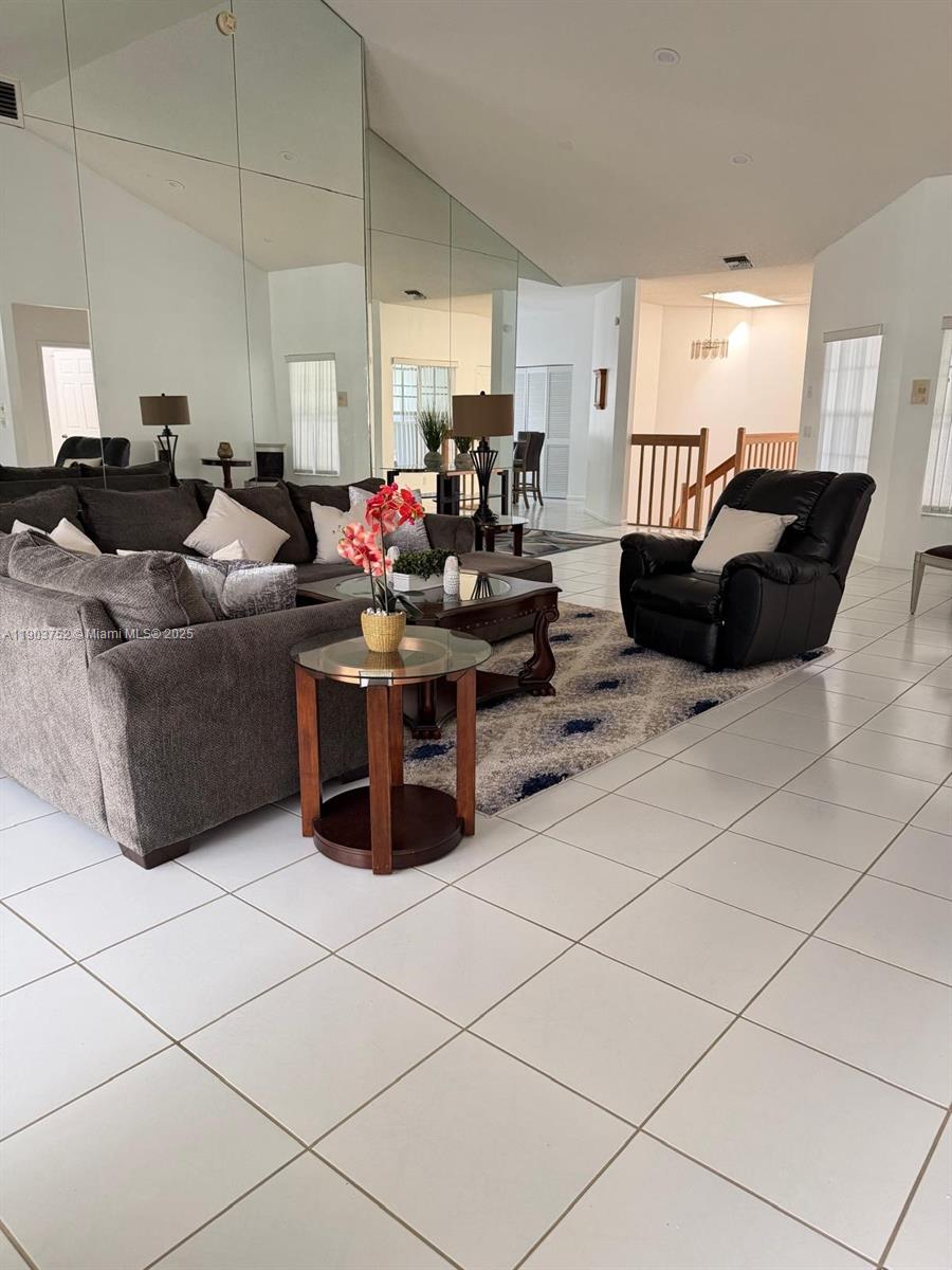A living room features white tile floors, a large mirrored wall, and a sectional sofa — 11690 Briarwood Cir # 4, Boynton Beach FL 33437, BOYNTON BEACH, FL