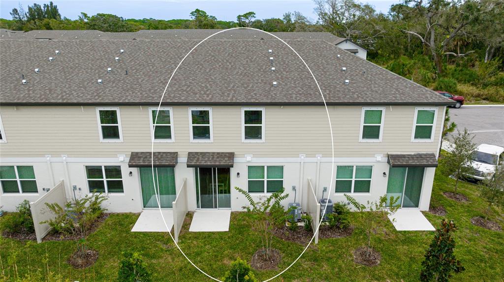 An exterior view of the rear of a two-story townhouse with beige siding and patios — 17063 CORAL KEY DRIVE, NOKOMIS, FL