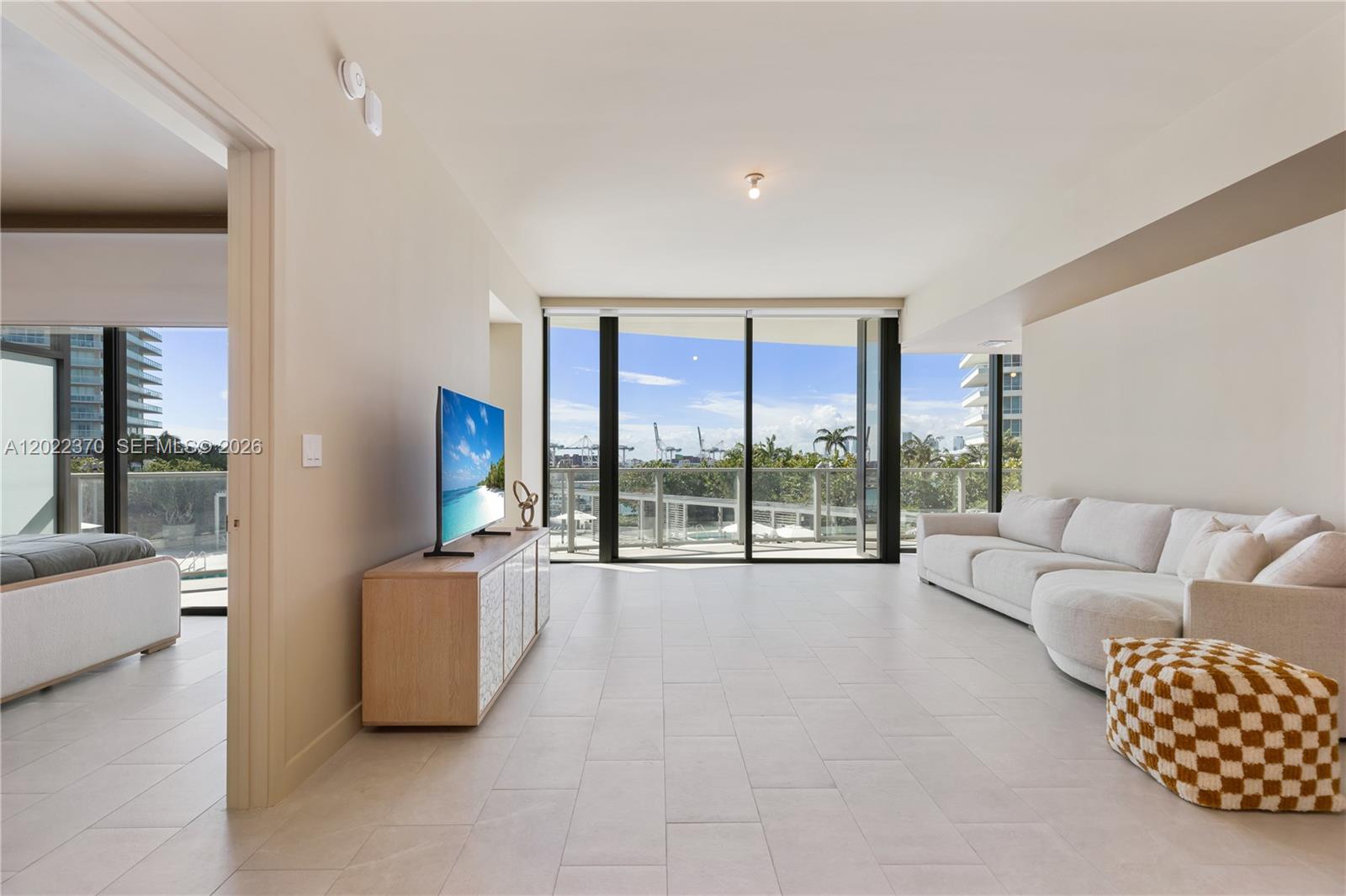 A modern living room features light tile floors, a white sofa, and floor-to-ceiling windows — 500 Alton Rd # 802, Miami Beach FL 33139, MIAMI BEACH, FL