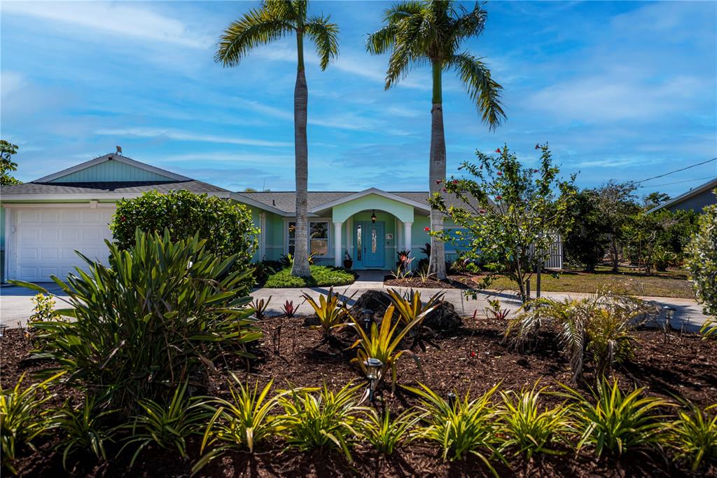 A single-story house with a light green exterior, a blue front door, and two tall palm trees — 1221 BAYSHORE DRIVE, ENGLEWOOD, FL