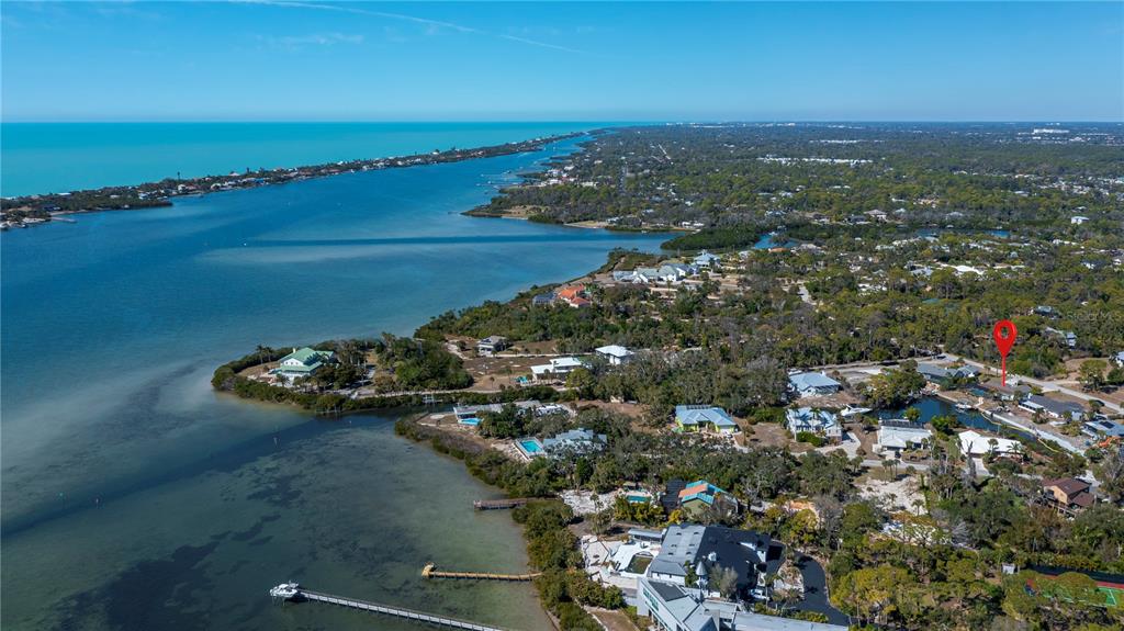 An aerial view shows waterfront homes along a coastline with a red location marker — 1221 BAYSHORE DRIVE, ENGLEWOOD, FL