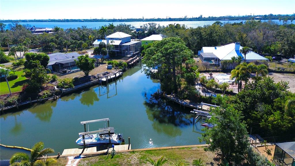 An aerial view shows waterfront houses with private docks and a boat on a canal — 1221 BAYSHORE DRIVE, ENGLEWOOD, FL