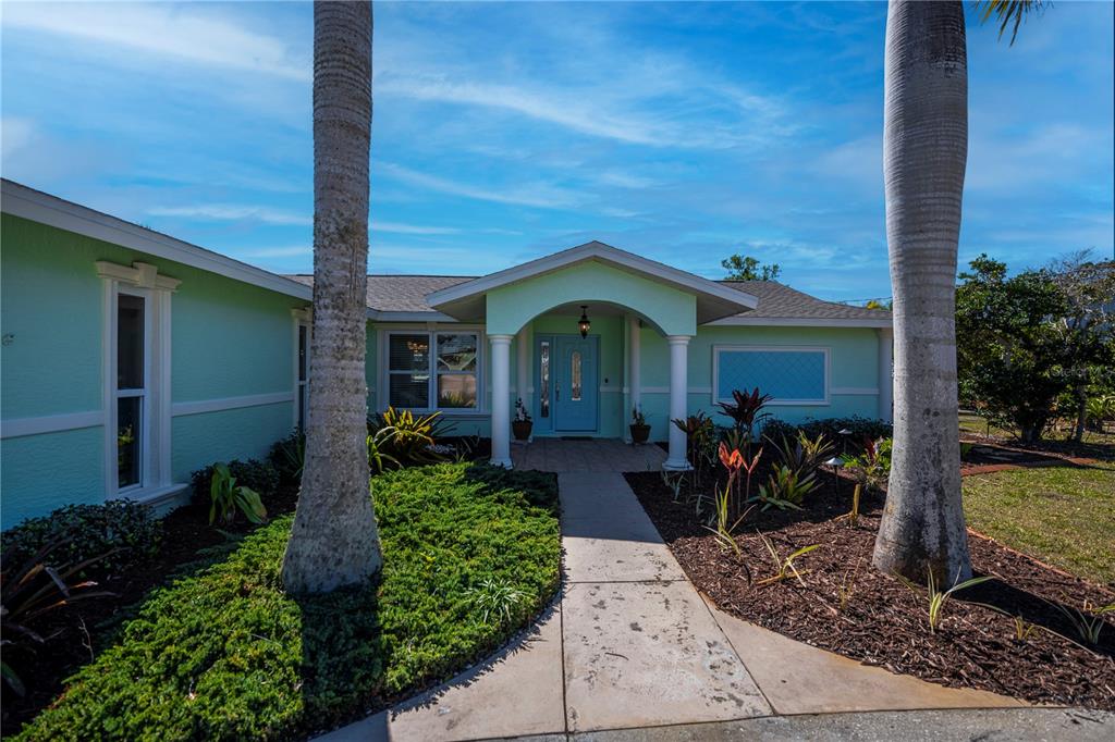 A light green house with a covered entryway, white columns, and a blue front door — 1221 BAYSHORE DRIVE, ENGLEWOOD, FL
