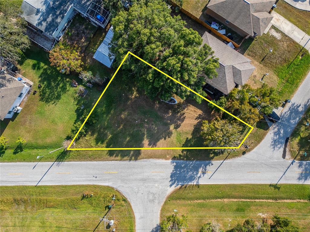 An aerial view shows a triangular vacant lot outlined in yellow next to residential houses — 1104 W COLLEGE AVENUE, RUSKIN, FL