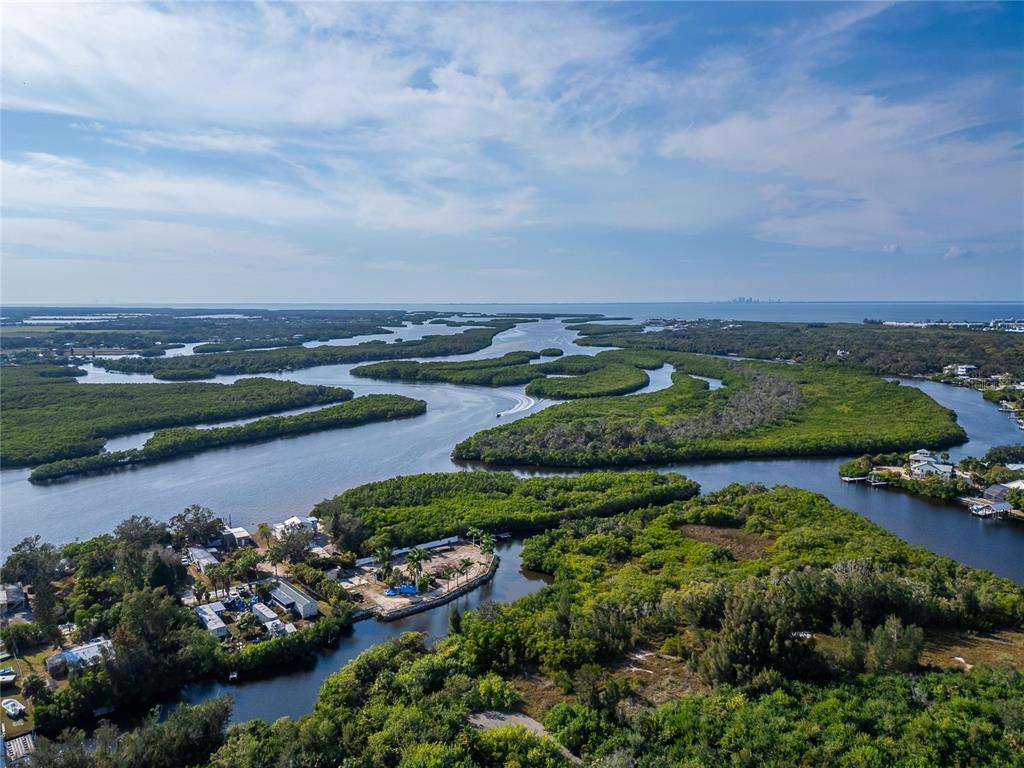 An aerial view shows a coastal landscape with winding waterways, mangrove islands, and residential properties — 1104 W COLLEGE AVENUE, RUSKIN, FL