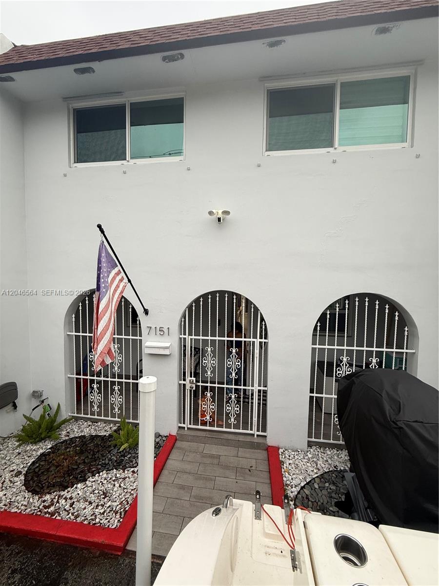 The exterior of a two-story building features white stucco walls, arched gated entrances, and windows — 7151 W 3rd Ct # 0, Hialeah FL 33014, HIALEAH, FL