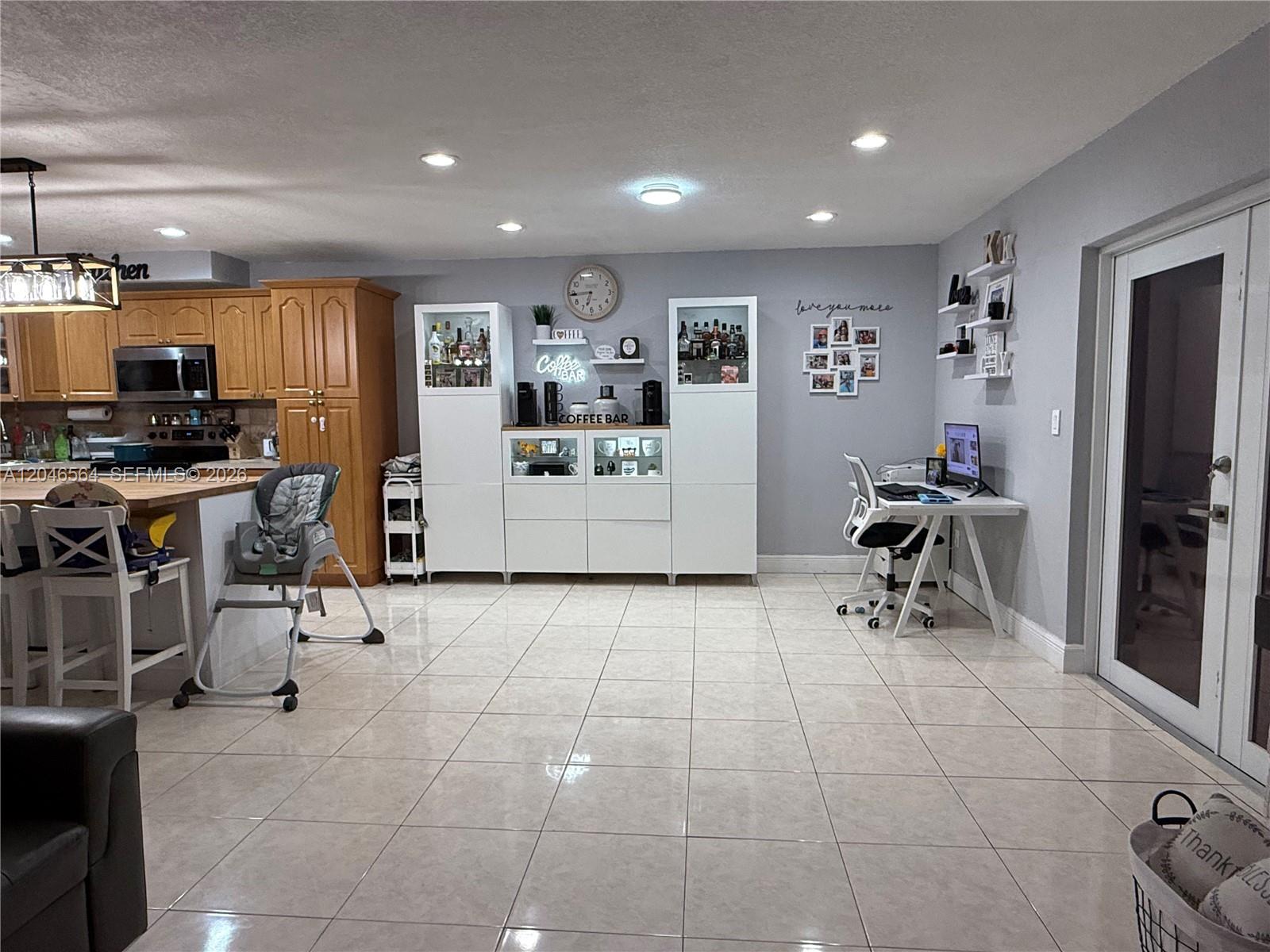 A kitchen and dining area features light tile floors, white cabinetry, and a small home office — 7151 W 3rd Ct # 0, Hialeah FL 33014, HIALEAH, FL