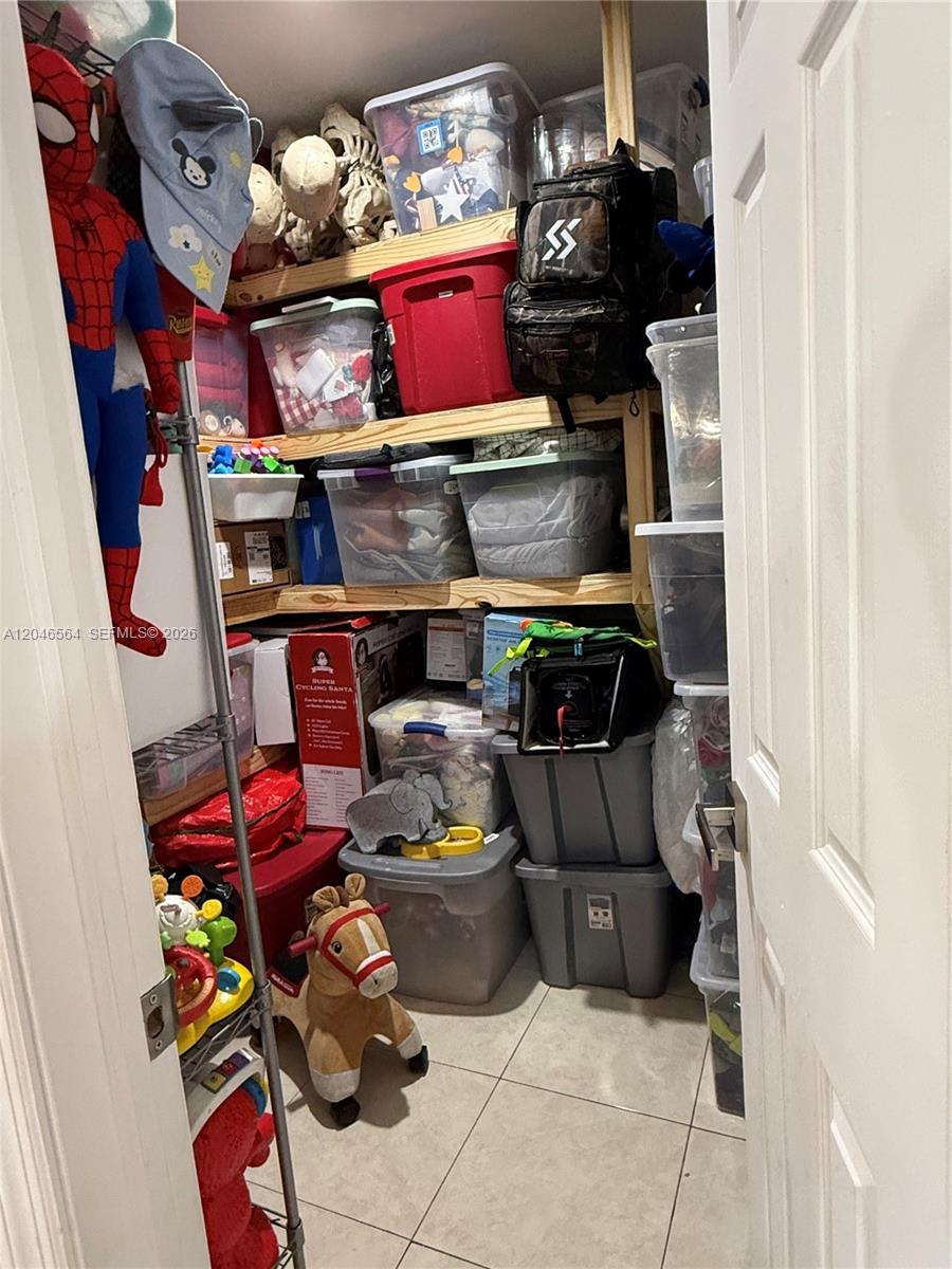 A small storage closet is filled with plastic bins, shelving units, and various toys — 7151 W 3rd Ct # 0, Hialeah FL 33014, HIALEAH, FL
