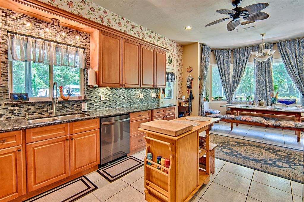 A kitchen with wood cabinets, granite countertops, a mobile island, and a dining area — 15522 SW 75TH STREET, ARCHER, FL
