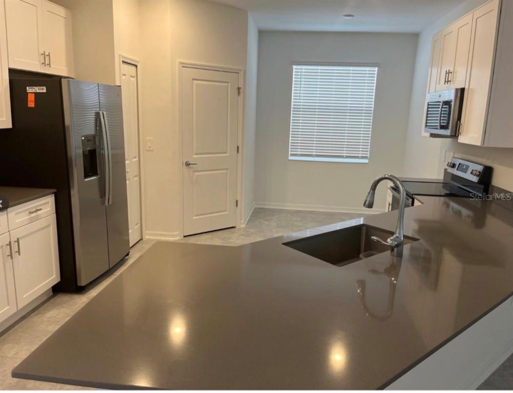 A kitchen features stainless steel appliances, white cabinets, and a large gray quartz island — 855 TURNER LANE, WINTER HAVEN, FL