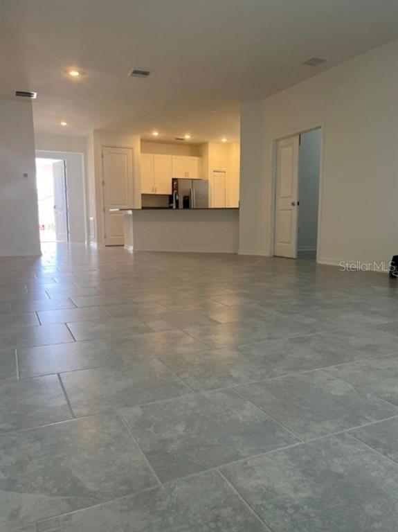 An open-concept living area features light-colored tile flooring and a kitchen with white cabinetry — 855 TURNER LANE, WINTER HAVEN, FL