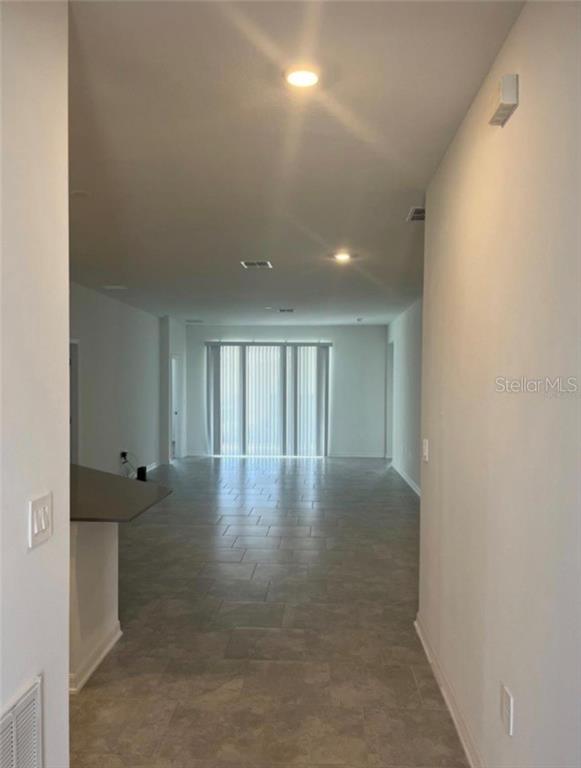 An interior view shows a long, open-concept room with light-colored tile flooring and recessed lighting — 855 TURNER LANE, WINTER HAVEN, FL