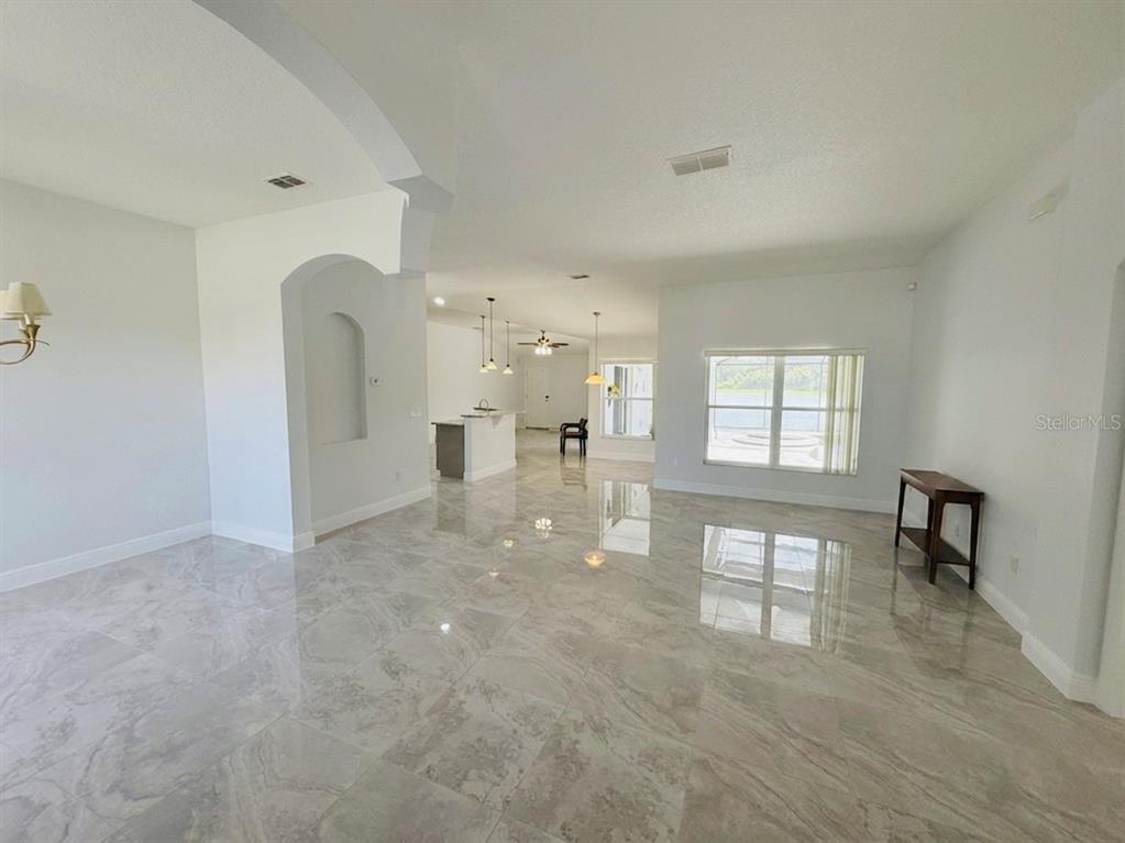 An open-concept living area features light-colored tile flooring, white walls, and a kitchen island — 3133 RIACHUELO LANE, KISSIMMEE, FL