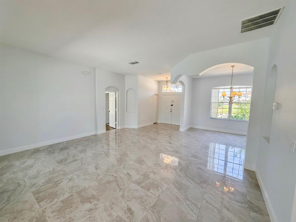 A bright, open-concept living area features polished marble tile flooring and a large arched window — 3133 RIACHUELO LANE, KISSIMMEE, FL