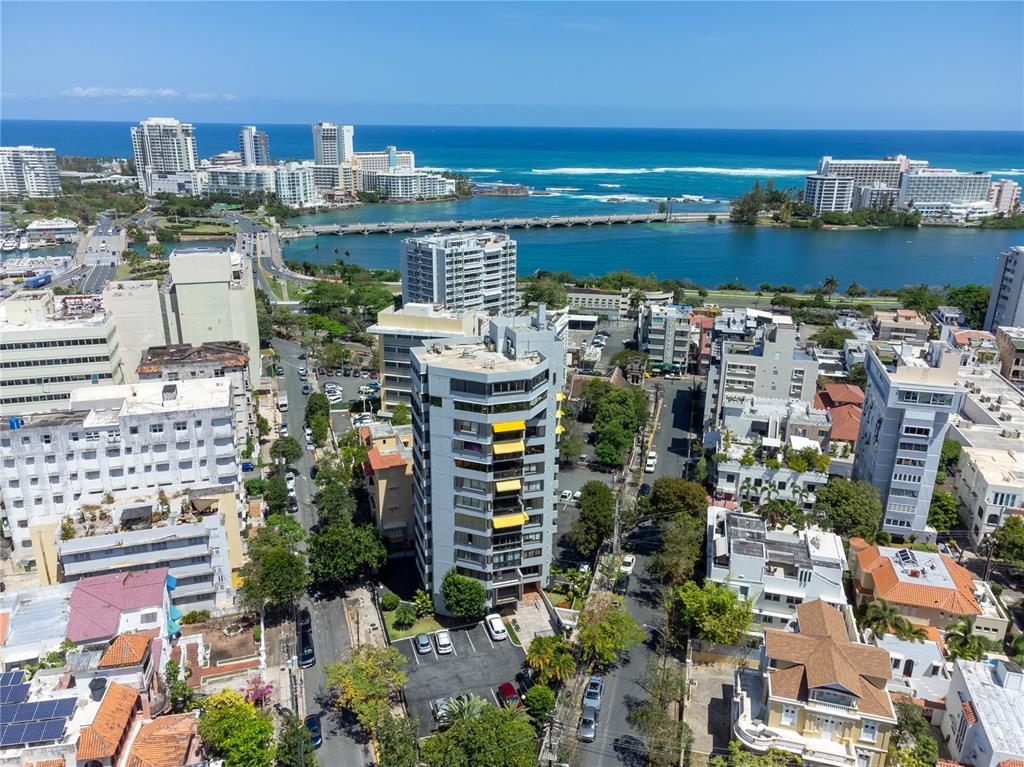 An aerial view shows a multi-story apartment building surrounded by city streets and a coastal lagoon — 610 AVE. MIRAMAR UNIT 5-B, SAN JUAN, PR