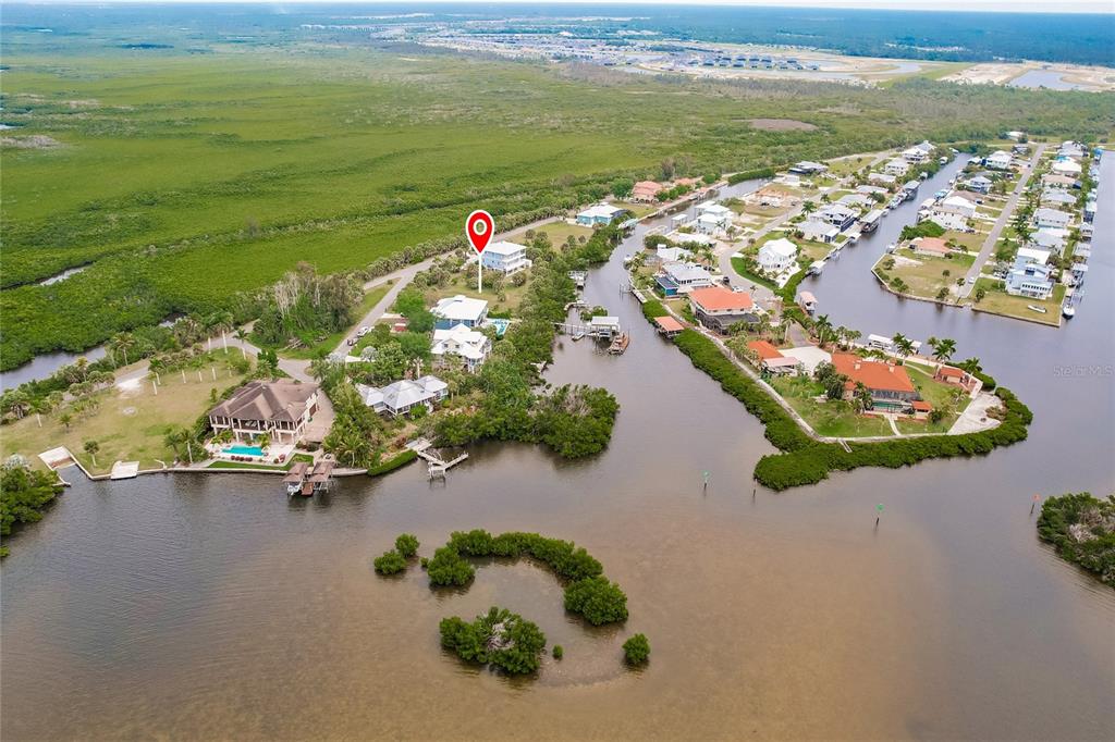 An aerial view shows waterfront houses surrounded by mangroves and canals with a location marker — 24169 JOLLY ROGER BOULEVARD, PUNTA GORDA, FL