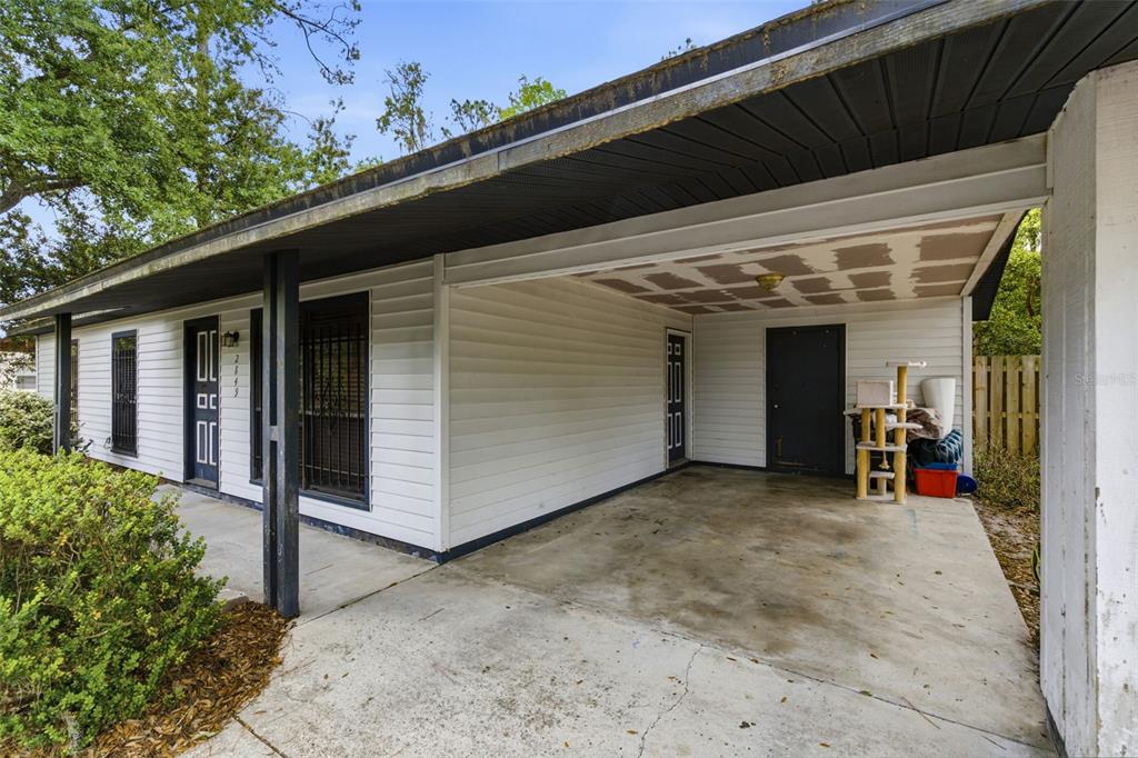 A white house exterior features a concrete carport, dark trim, and a covered front walkway — 2849 NW 57TH PLACE, GAINESVILLE, FL