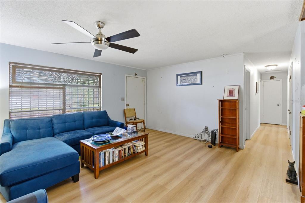 A living room features light wood-look flooring, a blue sectional sofa, and a ceiling fan — 2849 NW 57TH PLACE, GAINESVILLE, FL