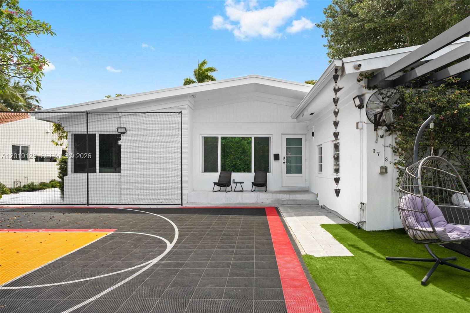 A white house exterior features a basketball court, artificial turf, and a hanging chair — 3758 Prairie Ave, Miami Beach FL 33140, MIAMI BEACH, FL