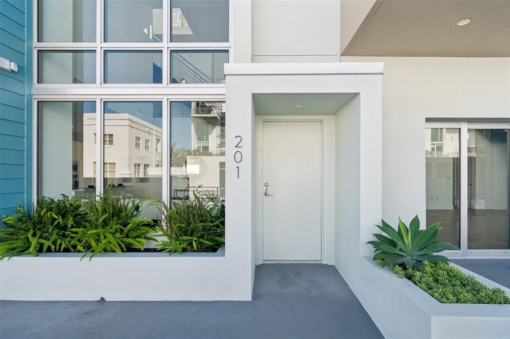 An exterior view of a modern building entrance with the number 201 and black lanterns — 1343 4TH STREET UNIT 202, SARASOTA, FL